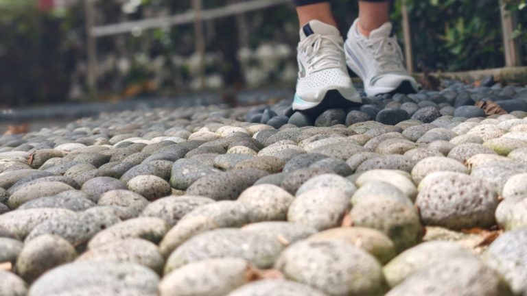 Person walking on a pebble path wearing sneakers